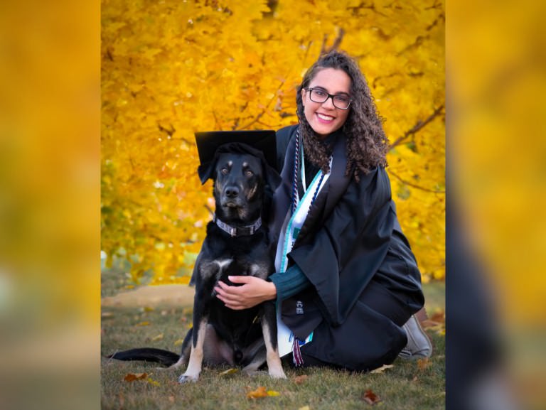 Olivia Davis with a dog in front of golden aspen trees