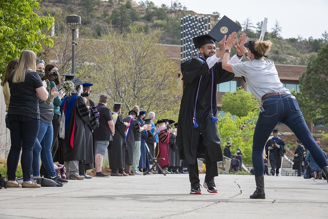 students high five staff and faculty at the picture on the plaza event