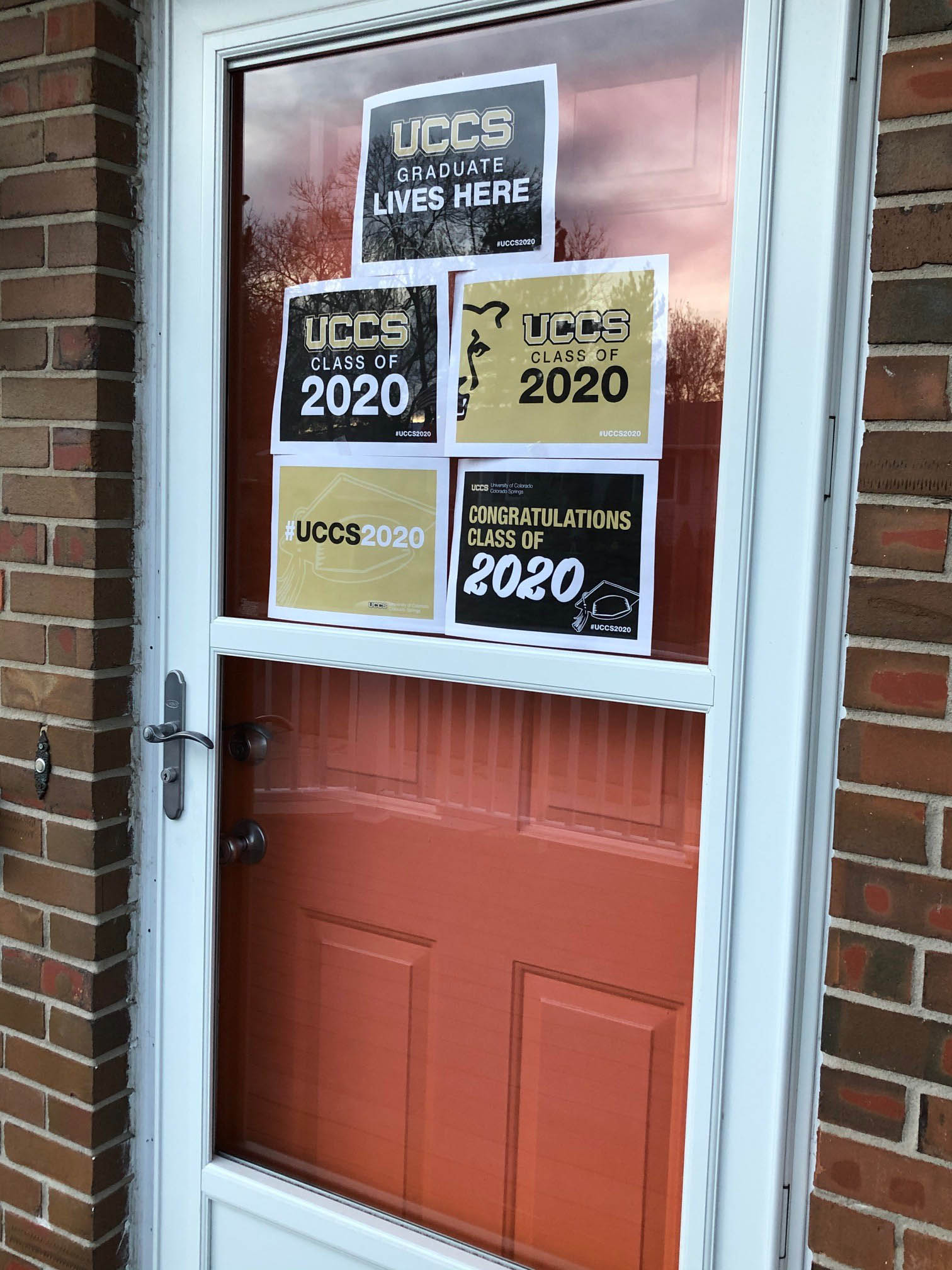 Signs created by UCCS are printed and displayed in a window in this narrow photo